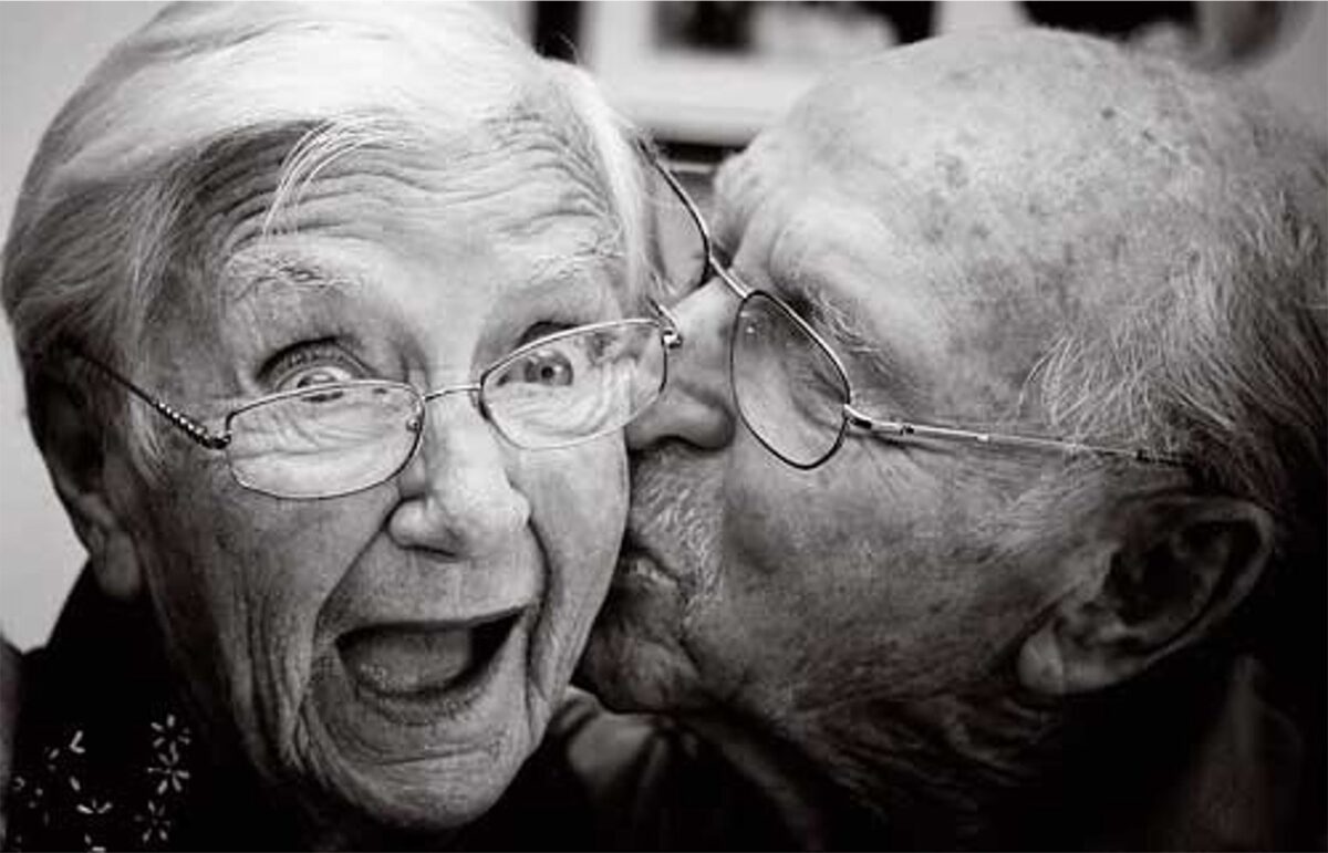 Elderly couple laughing as he kisses her cheek